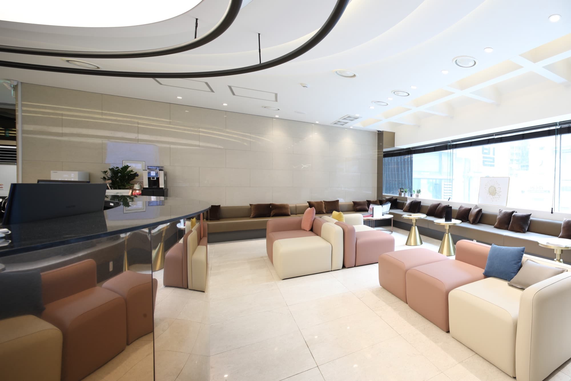 Bright waiting lounge with blush and cream modular sofas and floor-to-ceiling city-view windows