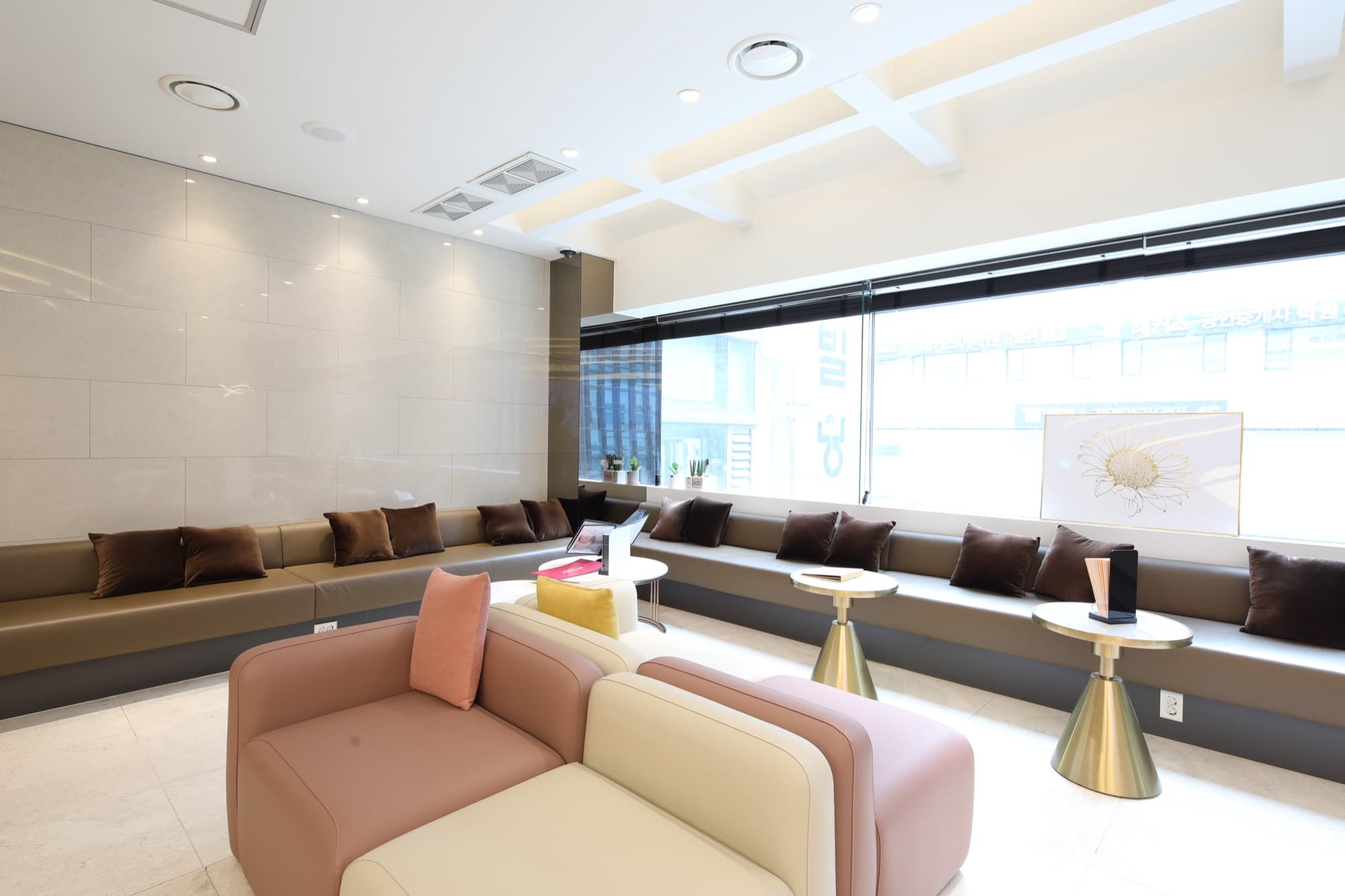 Cozy lounge corner with a pastel sofa, cushioned window bench and brushed-gold side tables