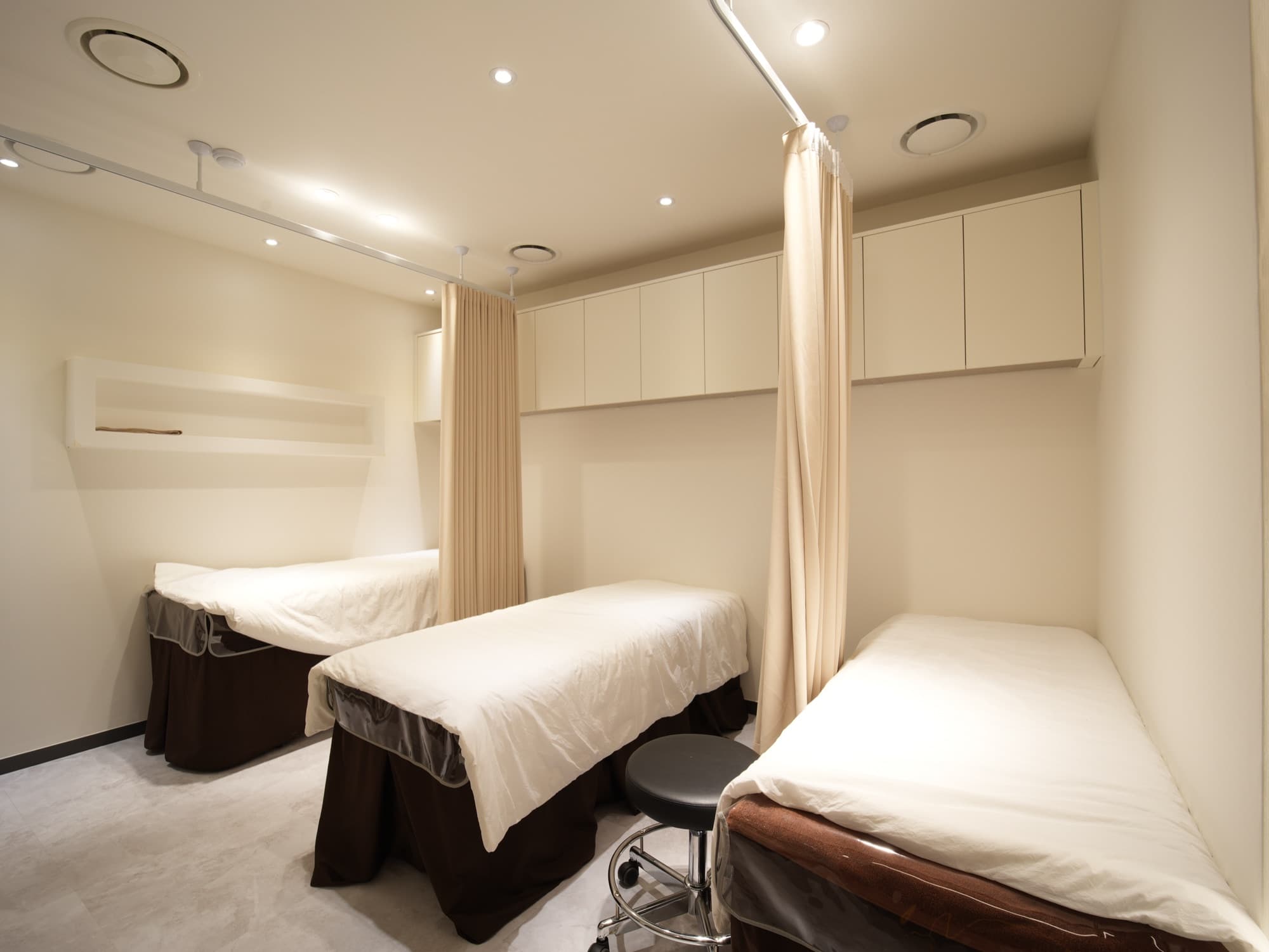 Quiet post-care recovery room with curtained resting beds and soft ambient lighting