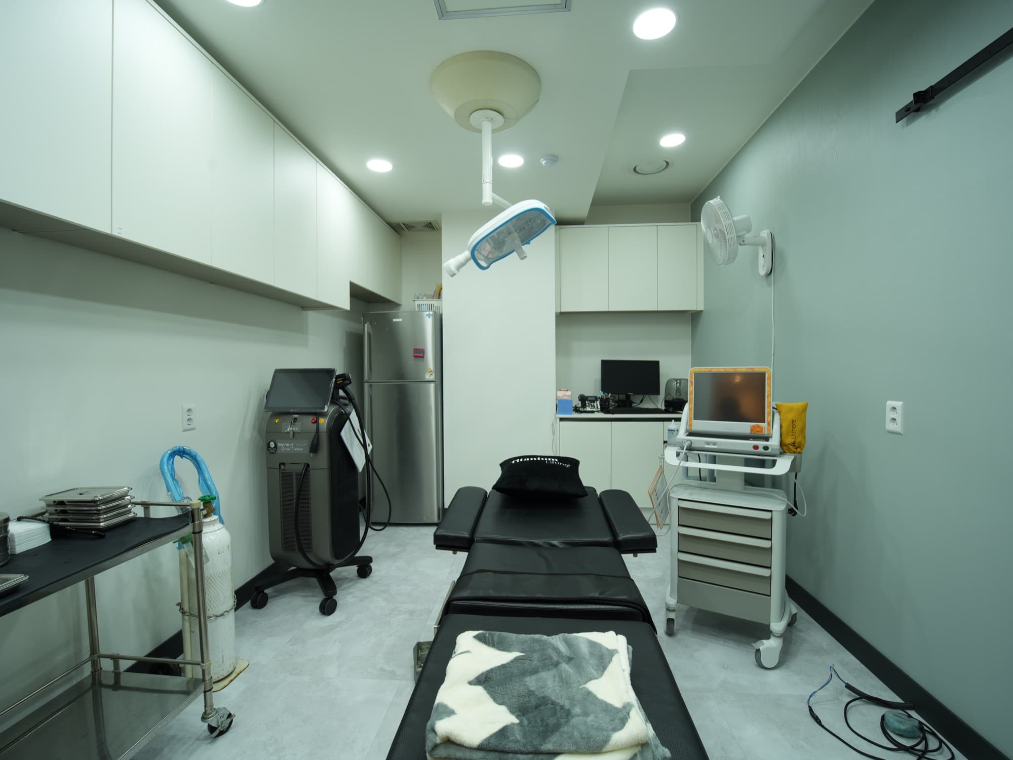Procedure room with a professional treatment bed surrounded by dedicated aesthetic laser equipment